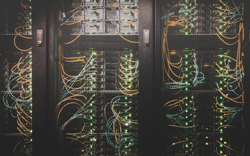 Server racks threaded with orange and teal fibre, status lights along each row