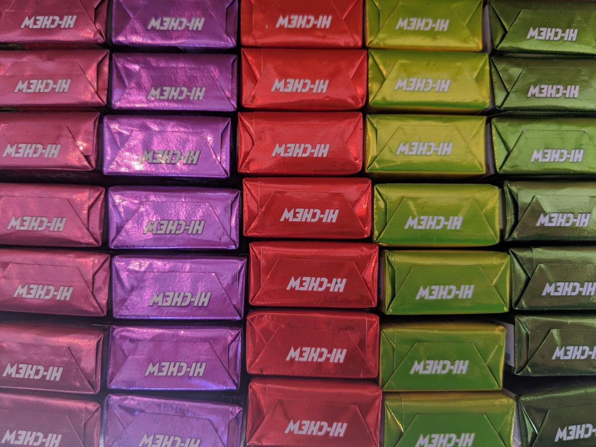 Rows of foil-wrapped candies in pink, purple, red and green, each stamped "HI-CHEW."