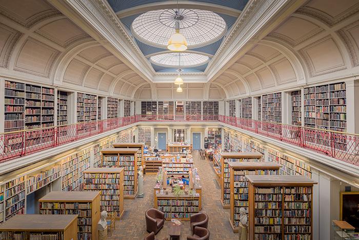 A grand two-story library with balconies of bookshelves under a domed skylight.