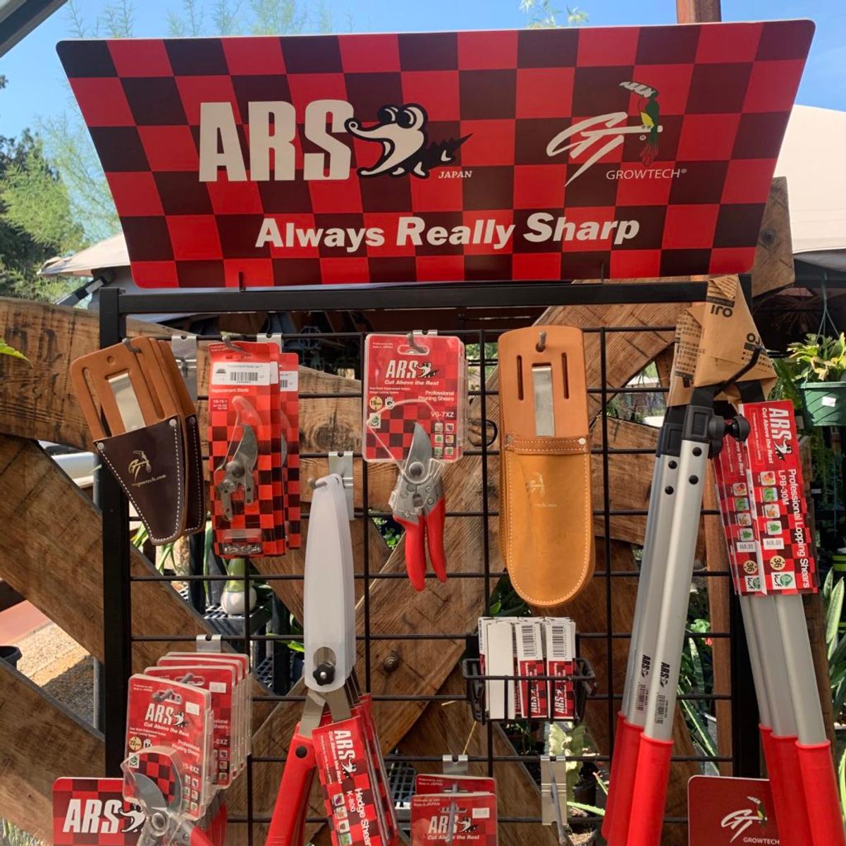 Garden tool display topped by a red checkered sign reading "ARS Japan — Always Really Sharp."