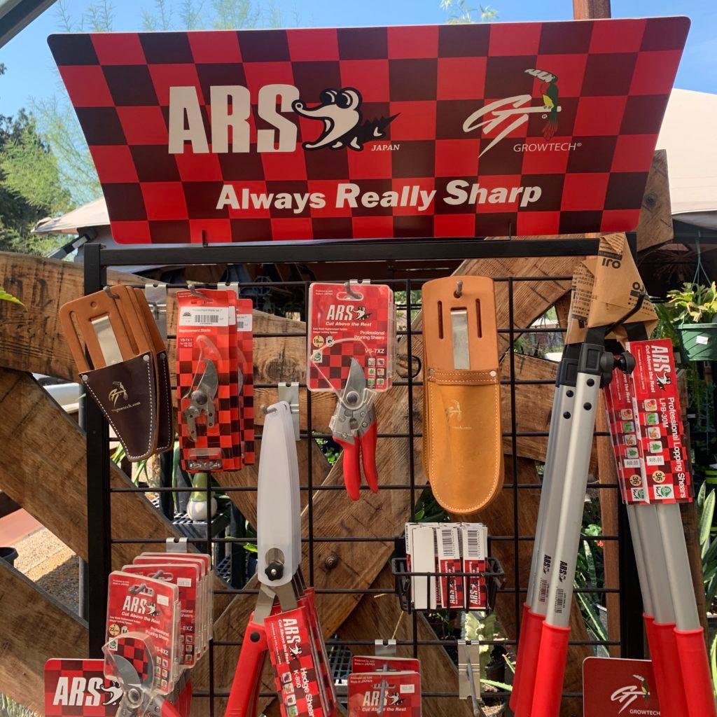 Garden tool display topped by a red checkered sign reading "ARS Japan — Always Really Sharp."