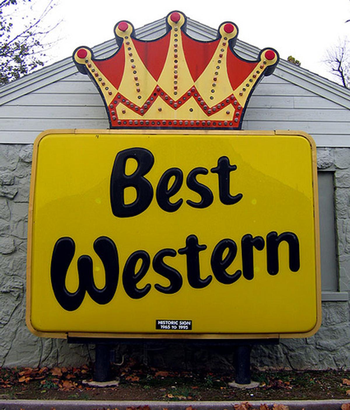 A yellow "Best Western" roadside sign topped with a red and gold crown.