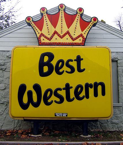A yellow "Best Western" roadside sign topped with a red and gold crown.