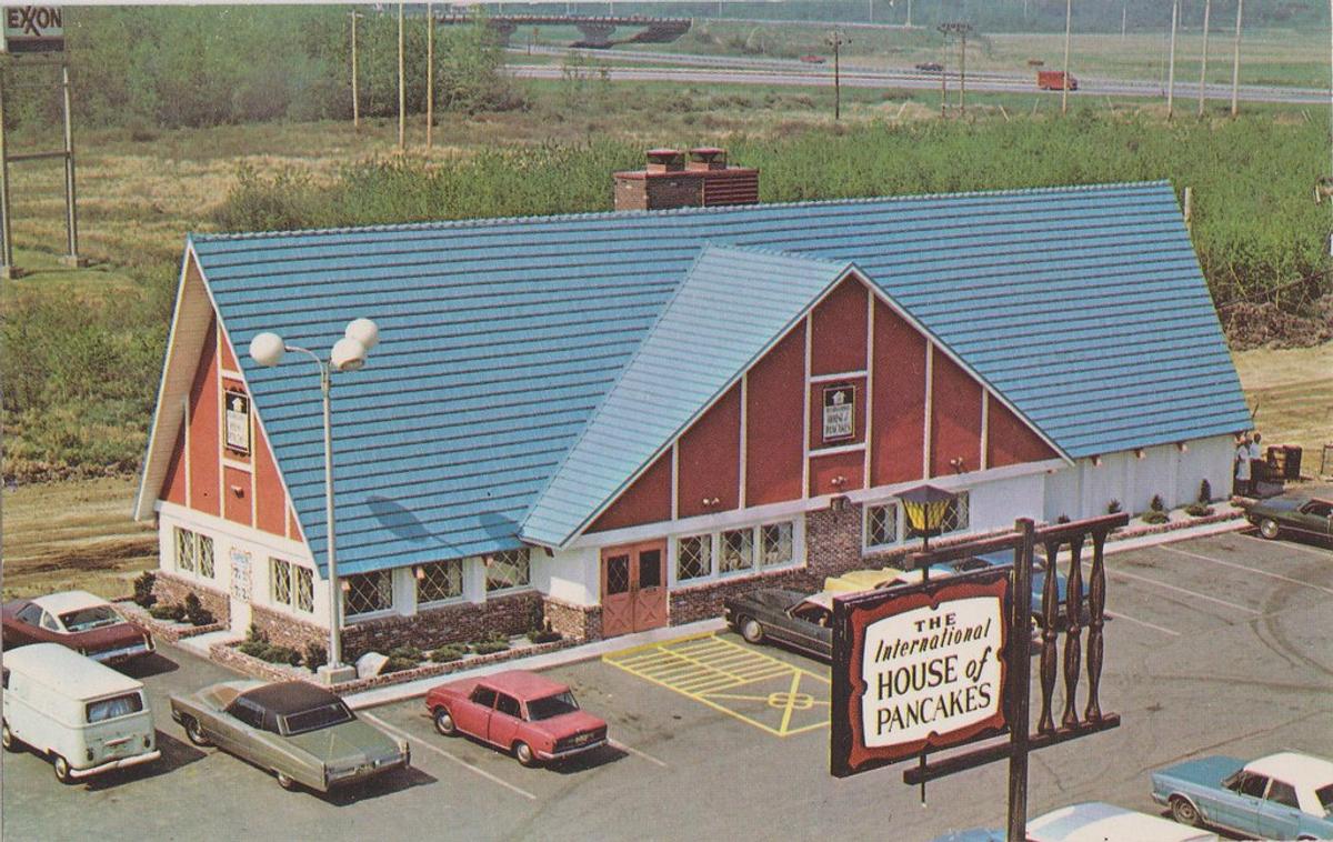 Vintage postcard of a blue-roofed chalet-style restaurant with a sign reading "The International House of Pancakes."