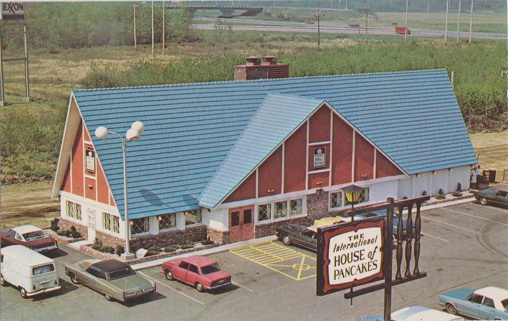 Vintage postcard of a blue-roofed chalet-style restaurant with a sign reading "The International House of Pancakes."