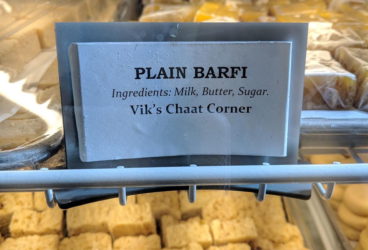 Sweets case label reading "PLAIN BARFI — Ingredients: Milk, Butter, Sugar. Vik's Chaat Corner."