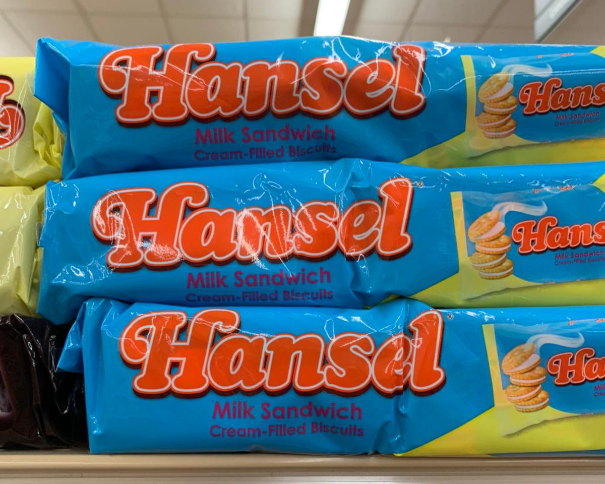 Blue packs of "Hansel Milk Sandwich Cream-Filled Biscuits" stacked on a shelf.