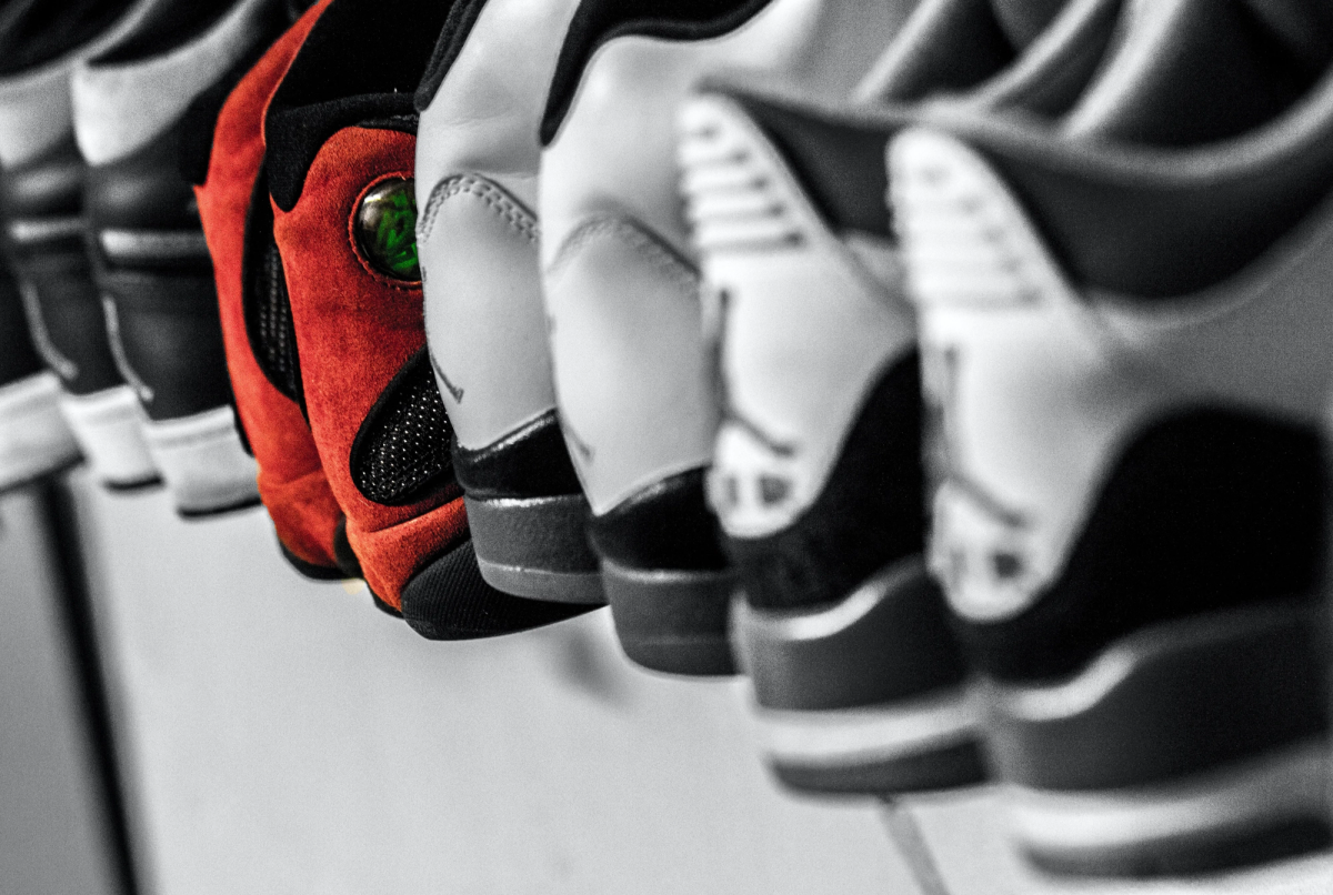 A row of sneakers in black and white, with one red suede pair standing out in color.