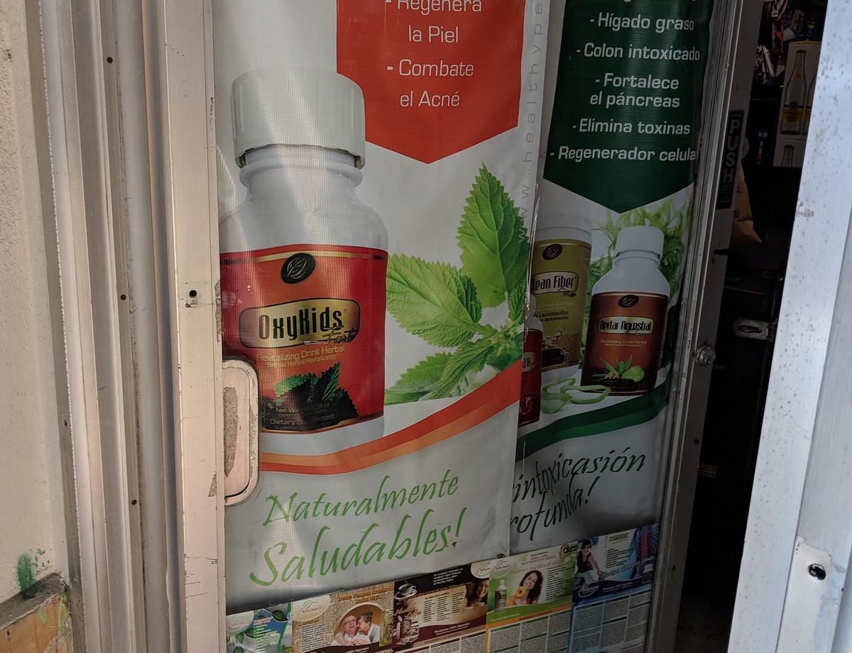 Shop-window banner for a supplement drink called "OxyKids," with the slogan "Naturalmente Saludables!"