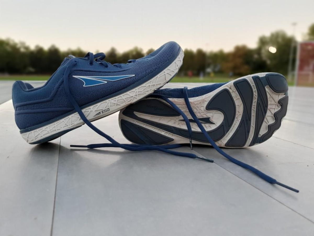 A pair of blue Altra running shoes with wide toe boxes and flat soles, one tipped on its side.