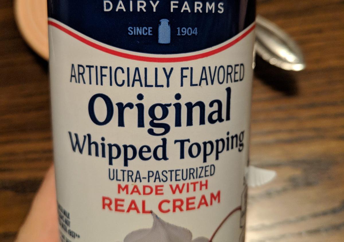 Whipped cream can labeled "Artificially Flavored Original Whipped Topping, Ultra-Pasteurized, Made With Real Cream" under "Dairy Farms, since 1904."