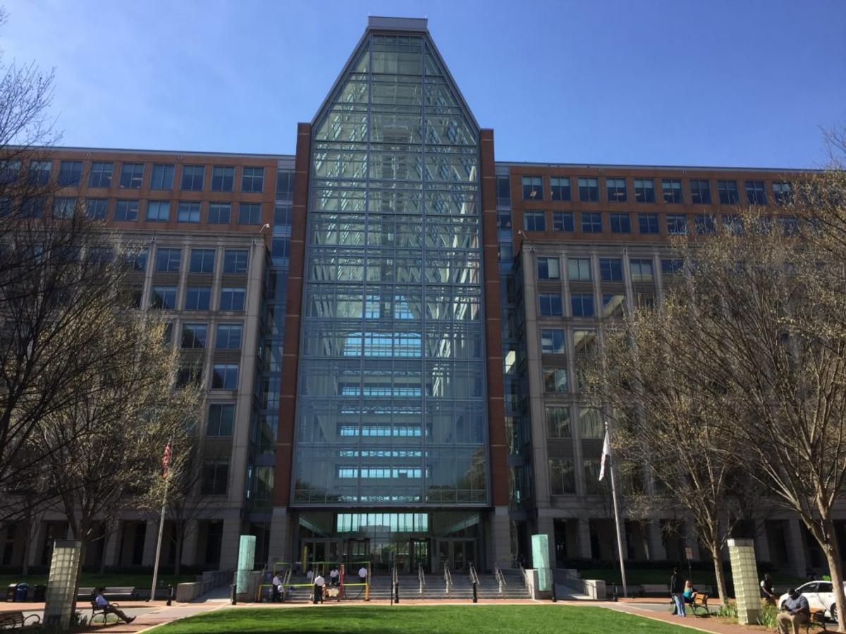 The USPTO headquarters in Alexandria, Virginia: a brick and glass office block with a tall glass atrium.
