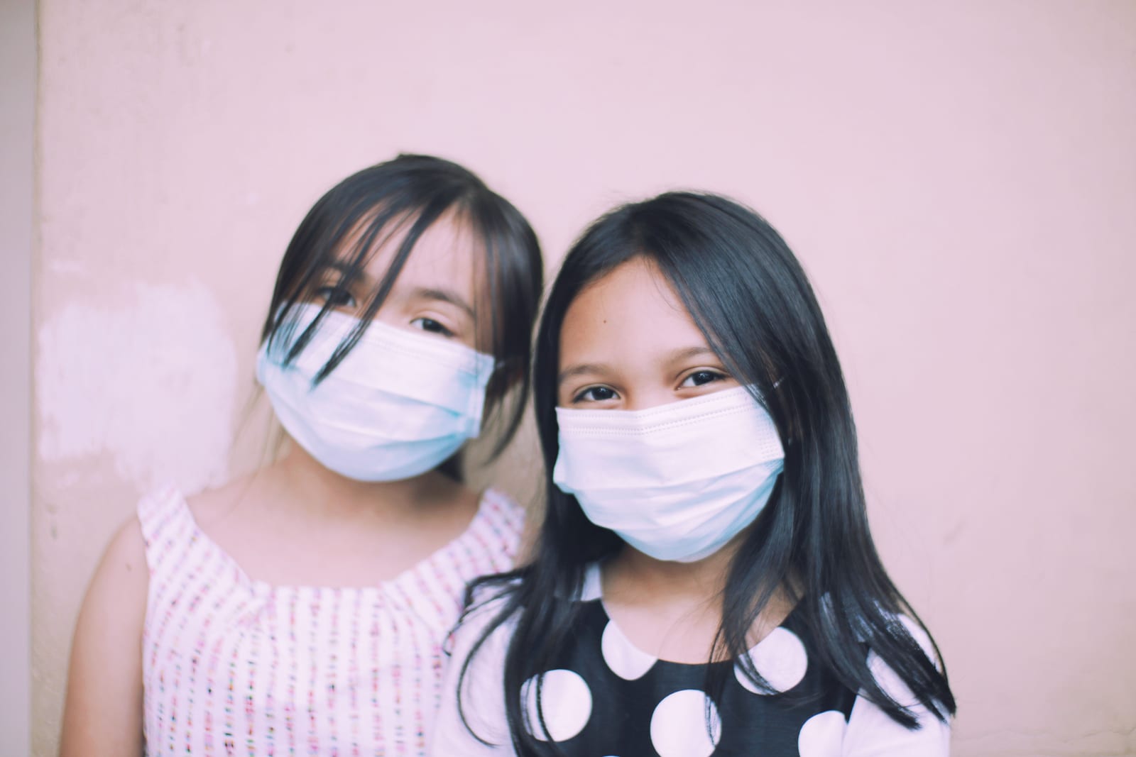 Two girls wearing face masks, looking at the camera.