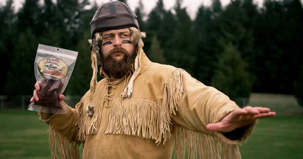 Old Trapper in a football pose but holding a bag of jerky instead of a football