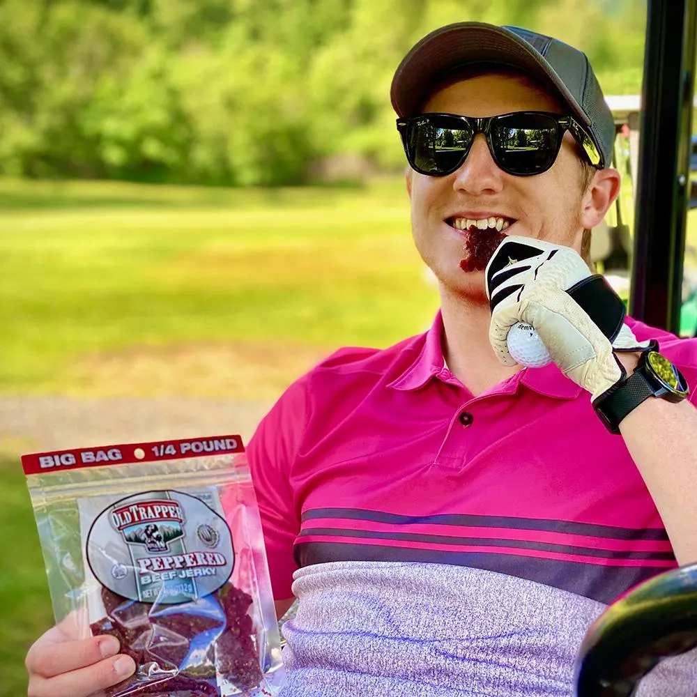 Guy in golf cart eating a bag of Old Trapper's Peppered Beef Jerky