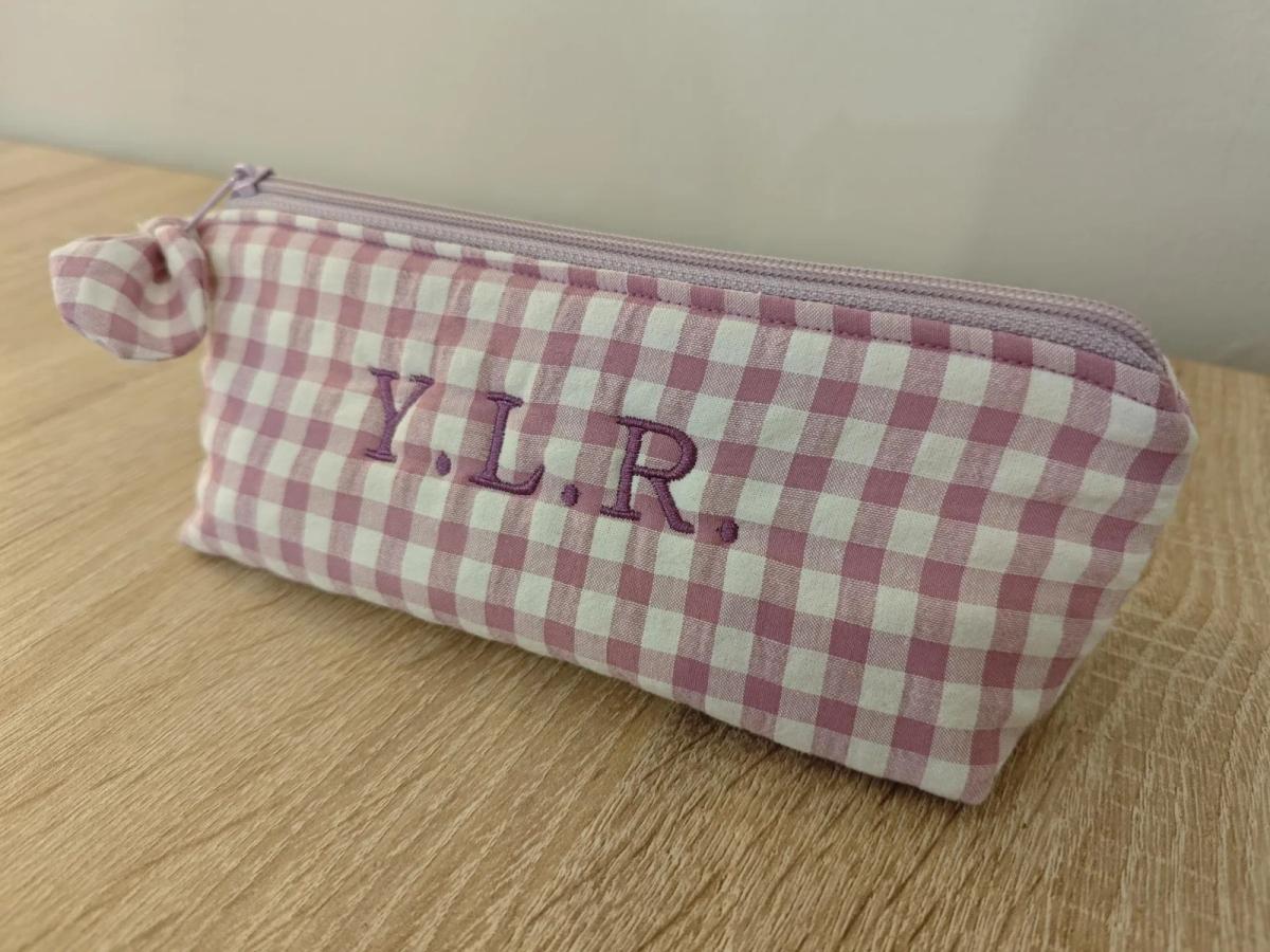 Estuche de vichy lila con las iniciales Y.L.R. bordadas en morado