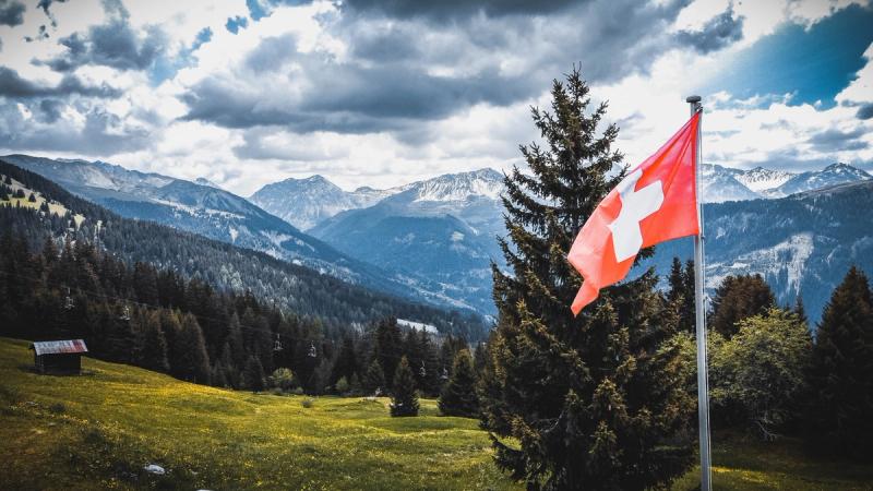 Swiss flag with alps in the background