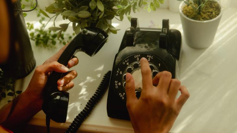 A person's fingers dialling on a rotary dial telephone.