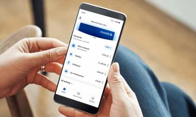 Hands holding a smartphone with Chase UK's mobile app open on the screen.