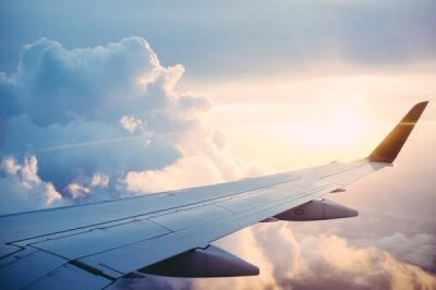 The wing of a commercial aircraft in the clouds during a flight.