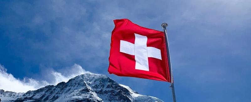 Swiss flag flying in front of the alps