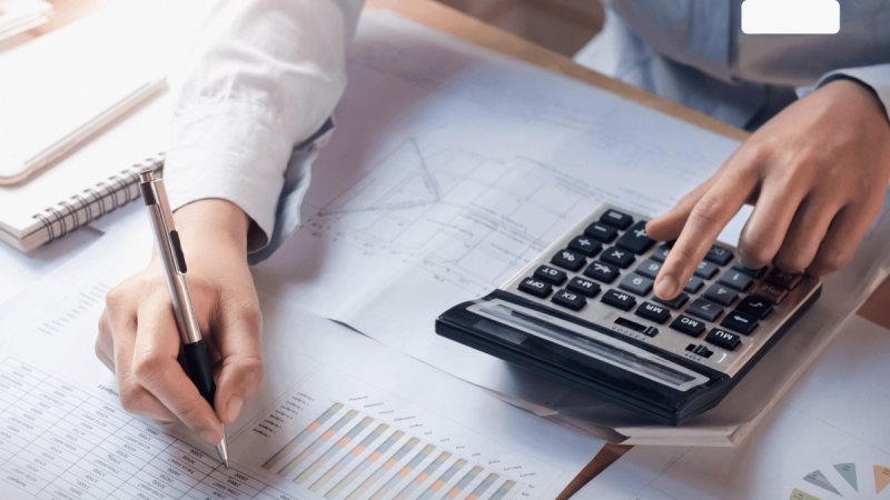 person with calculator, pen and paper doing tax calculations