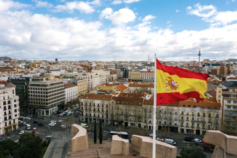 Flag of Spain raised with panorama of the city in the background