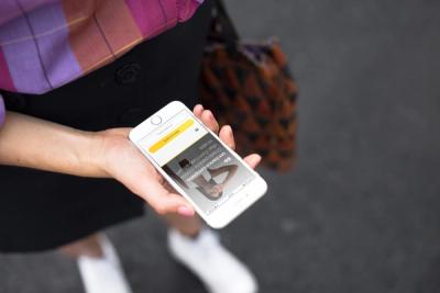 Mulher segura o smartphone na mão e acessa sua conta no app do C6 Bank