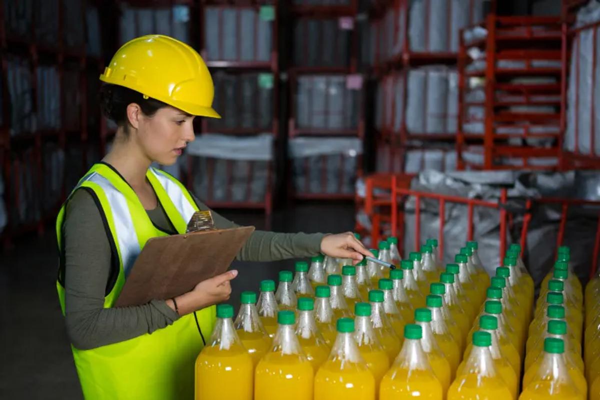 Operaria inspeccionando bebidas en una planta de producción