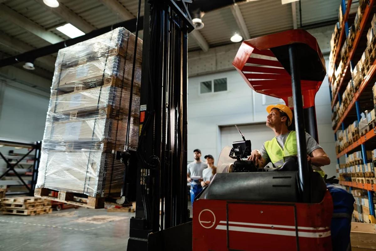 Operario en un montacargas elevando una estiba en una bodega