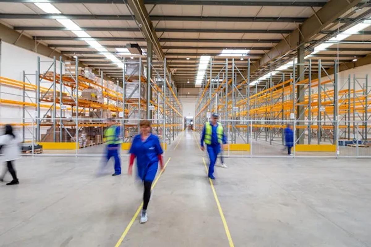Personal trabajando en una bodega de distribución con estanterías industriales