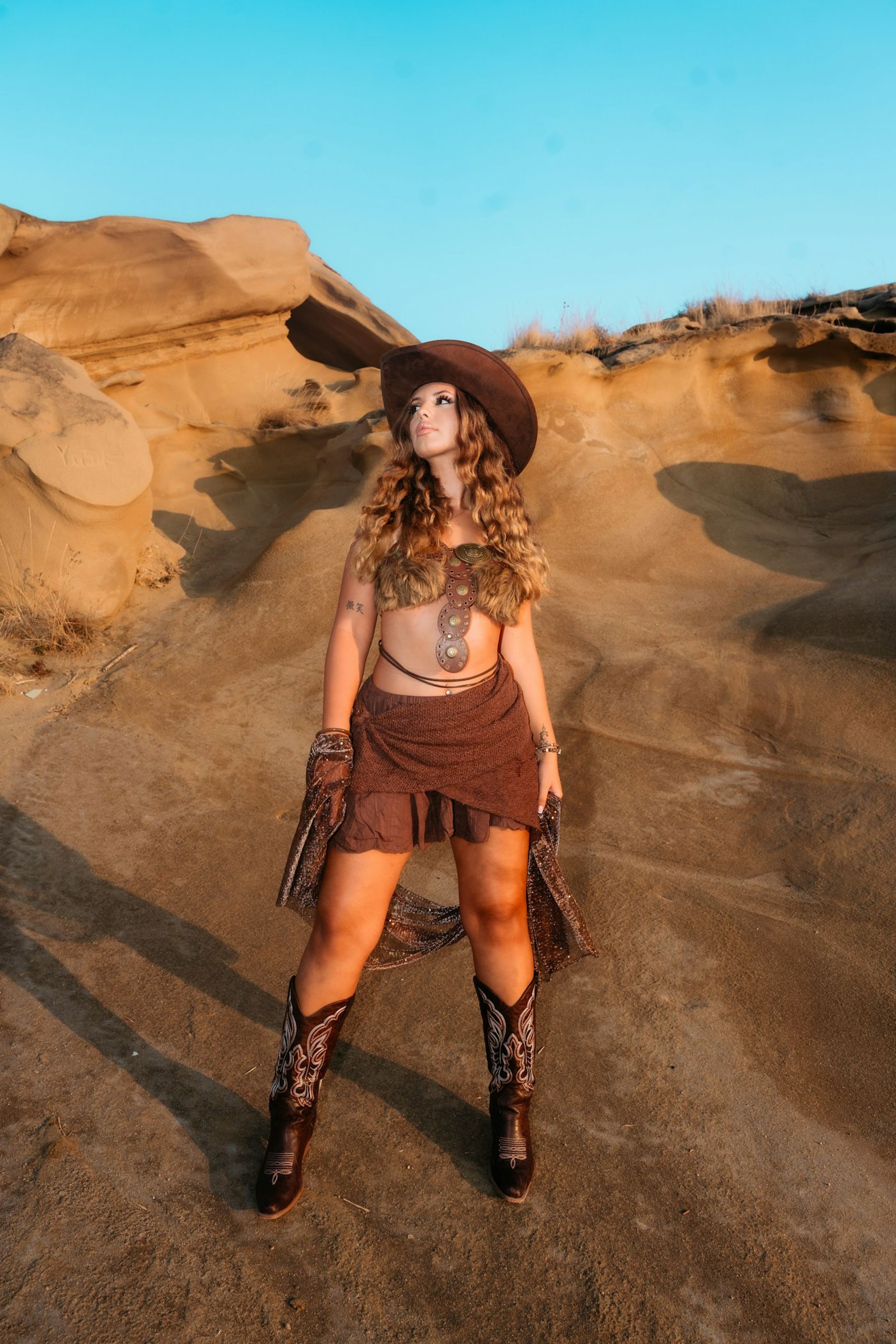 Woman in a western hat standing in a rocky desert landscape