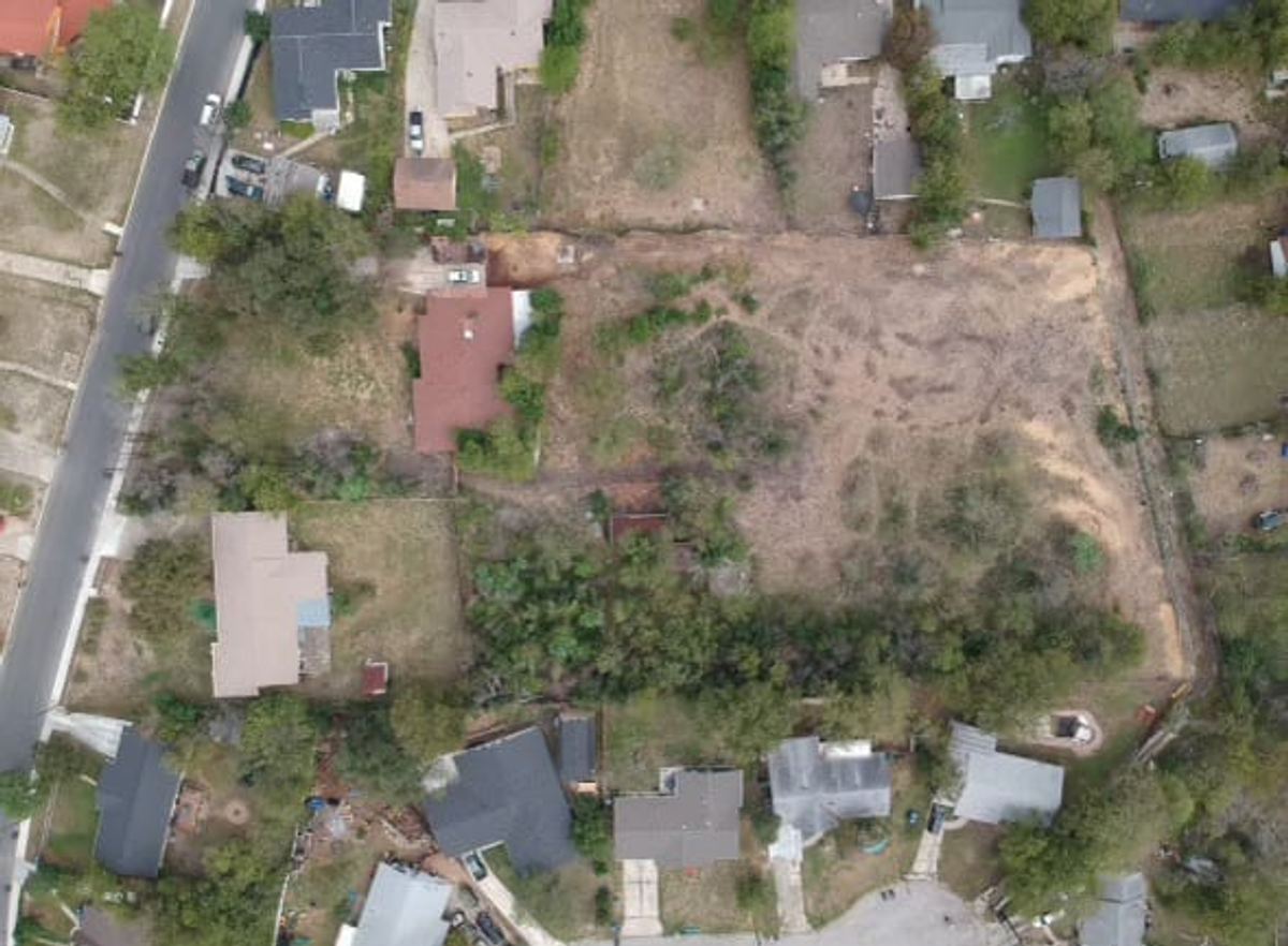 The property from the air before the farm: a red-roofed house and two overgrown acres, ringed by trees and neighbouring homes