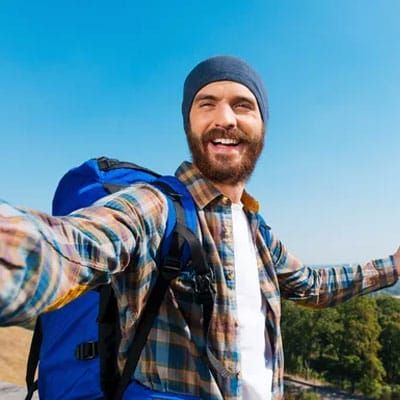 Man outside with backback in nature enjoying life.