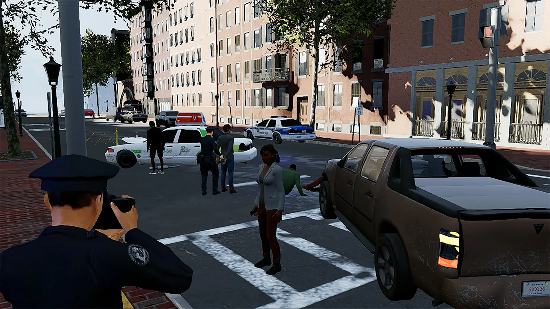 A police officer points a camera at the scene of a traffic collision. A second officer places someone in handcuffs in the distance.