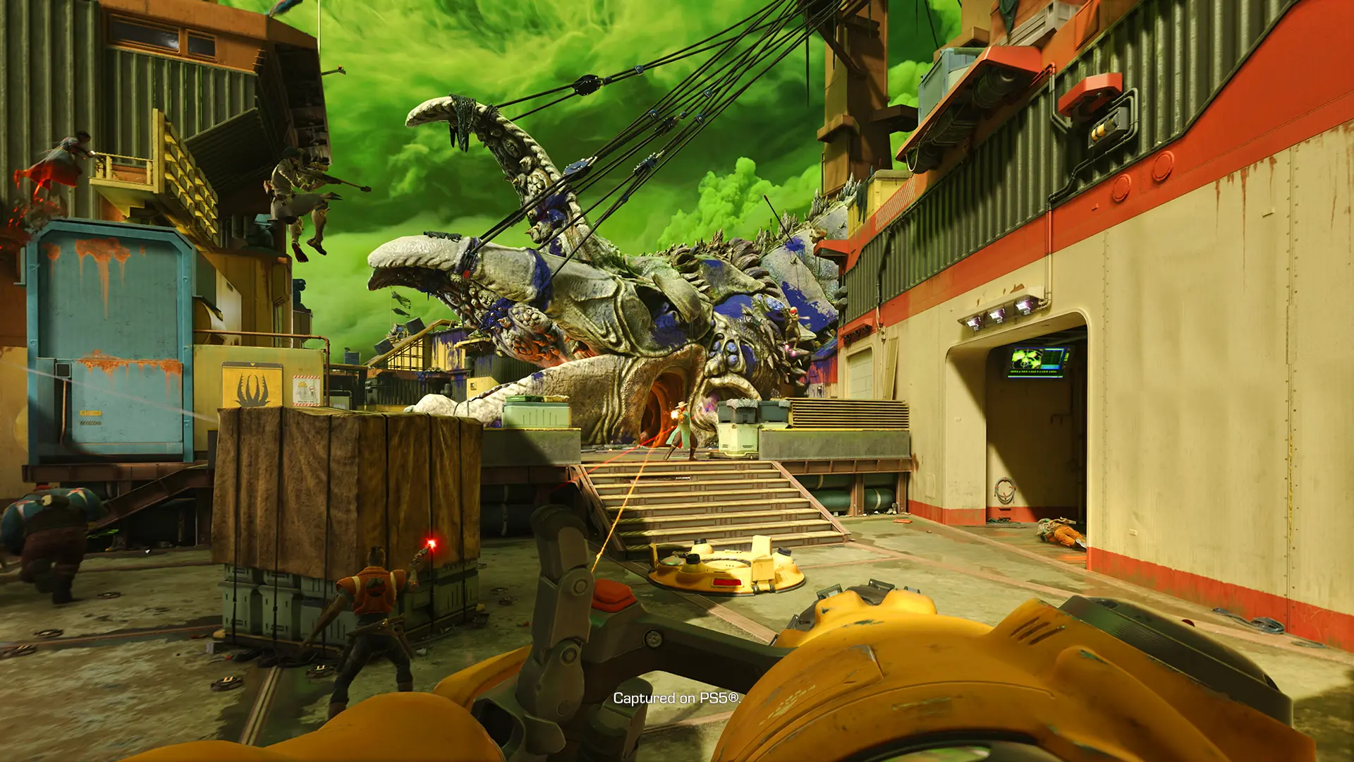 A player takes aim at an enemy on a sci-fi map with a gigantic alien creature in the background.