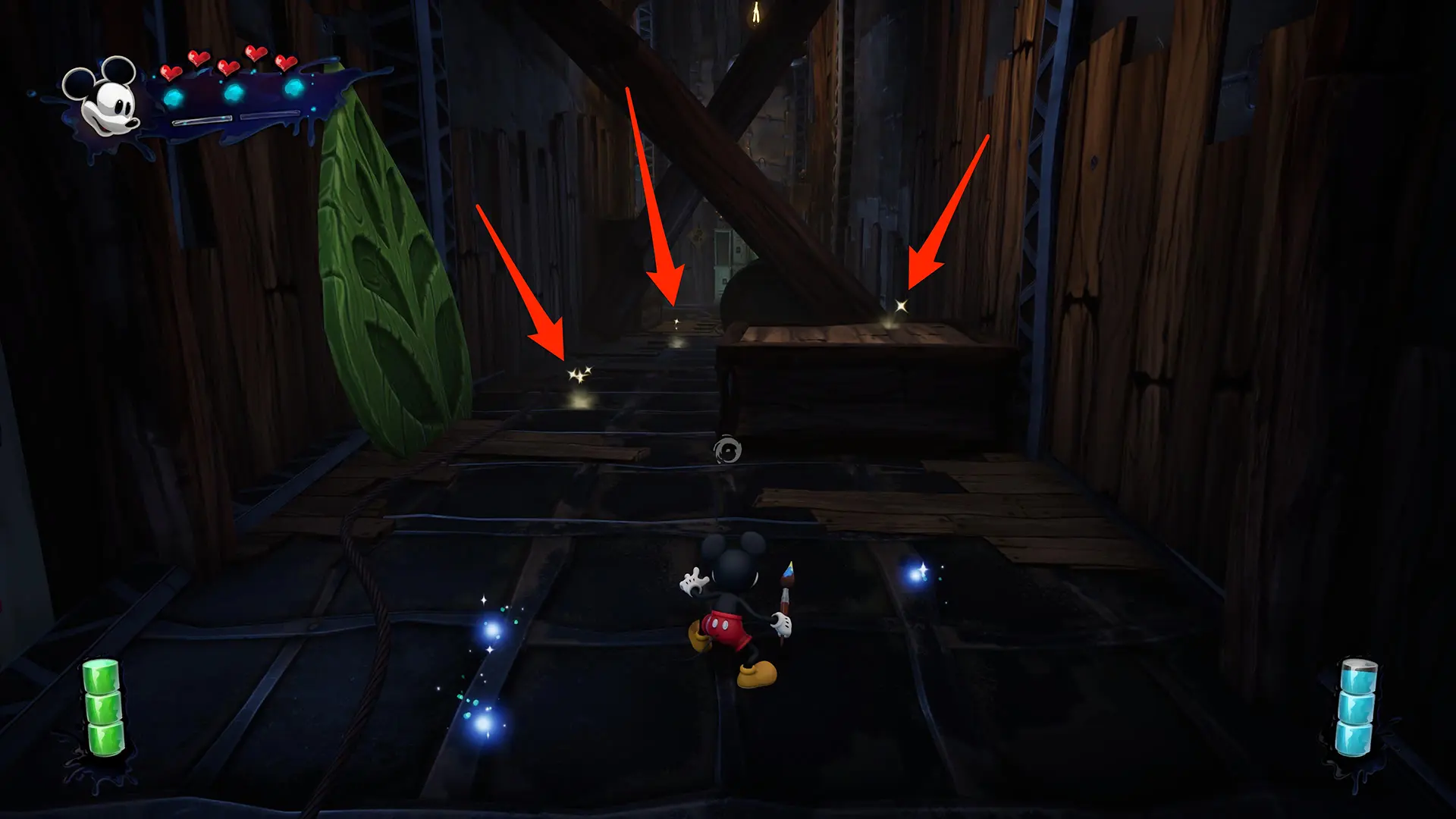 Three red arrows point at sparkles in a dark environment in the Epic Mickey: Rebrushed video game