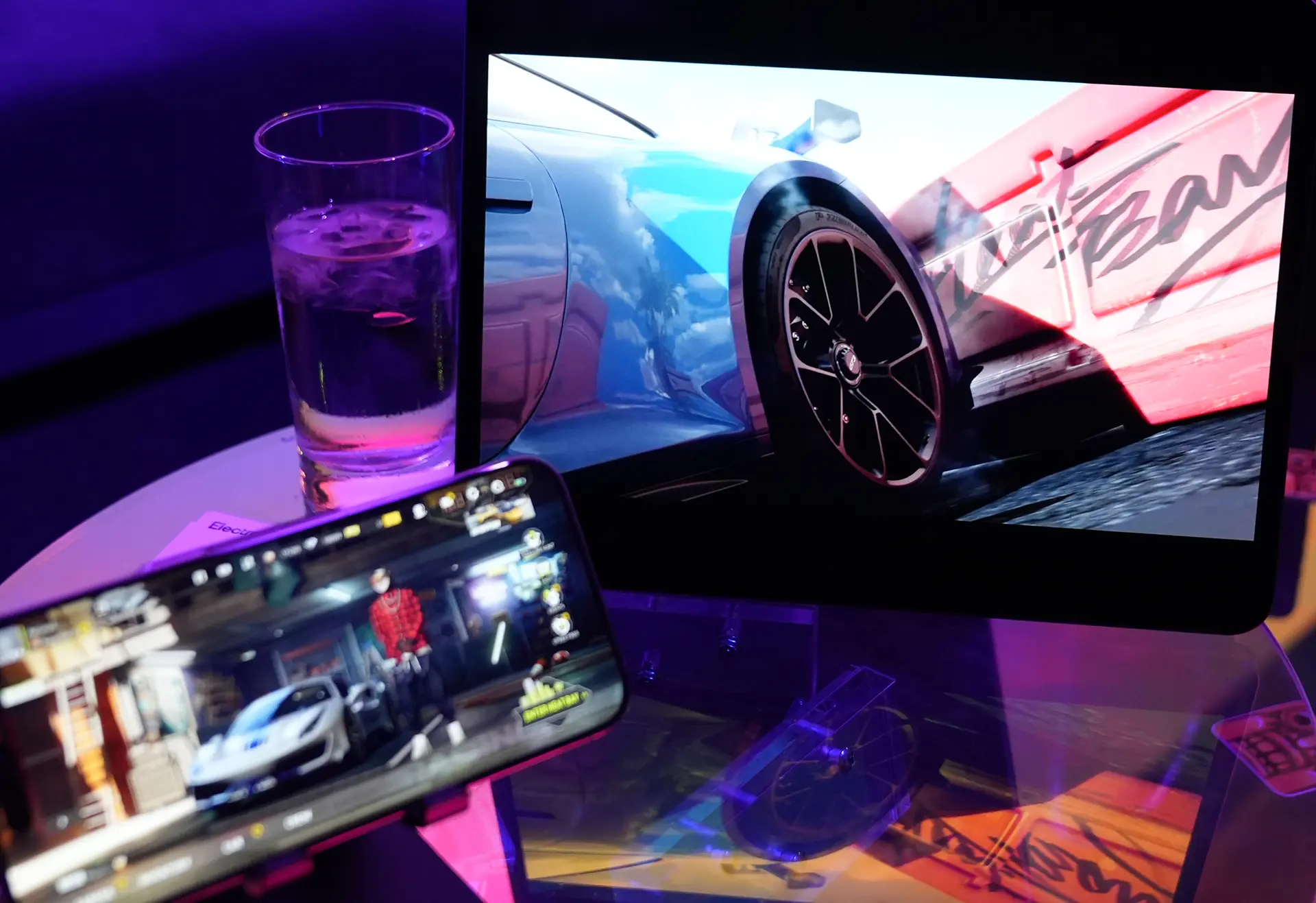 An iPhone and iPad on a glass table top with the Need for Speed Mobile game on the screen