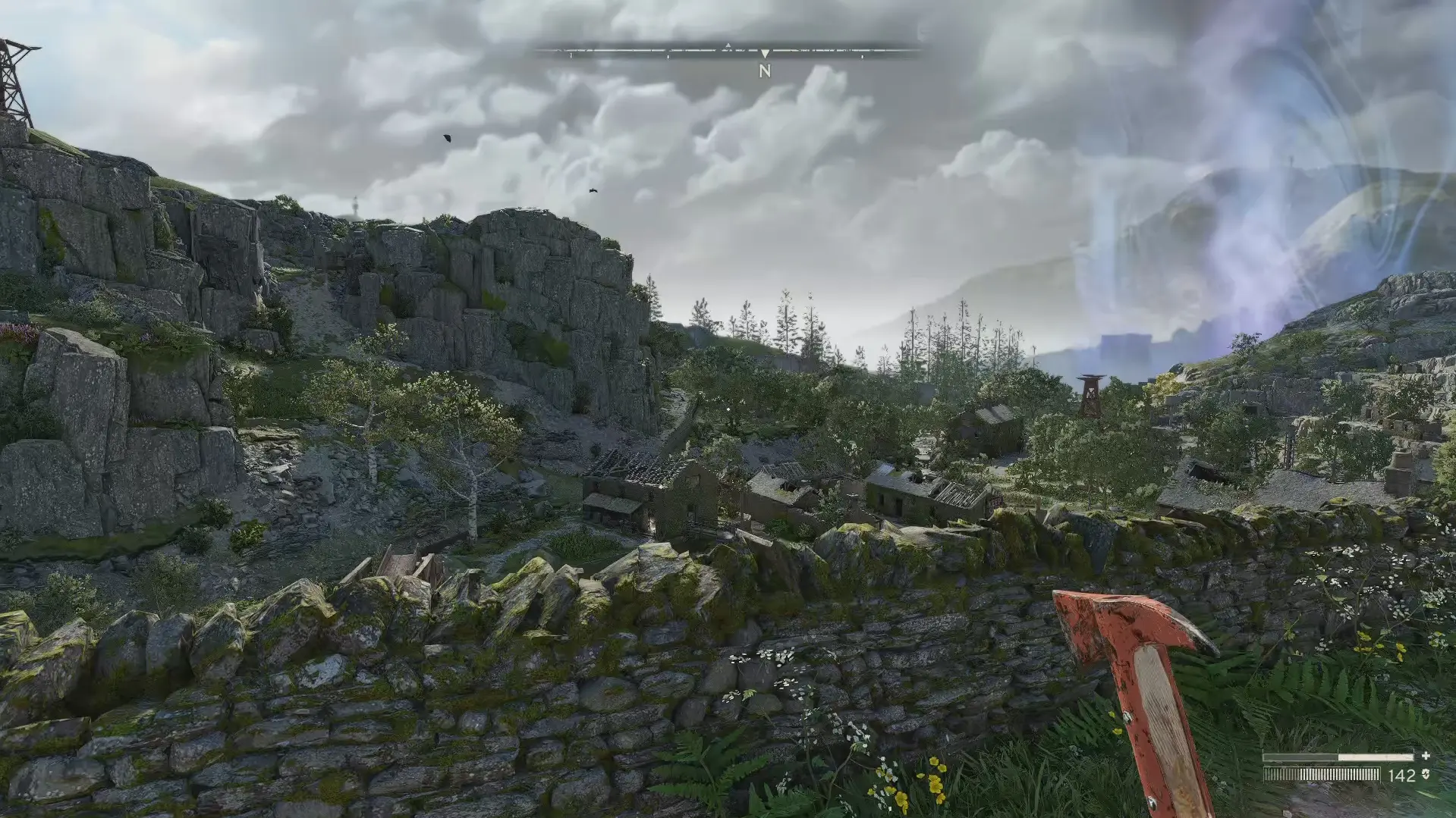 The player looks over a dry stone wall at the ruins of an English town. A supernatural aura appears in the distant air.