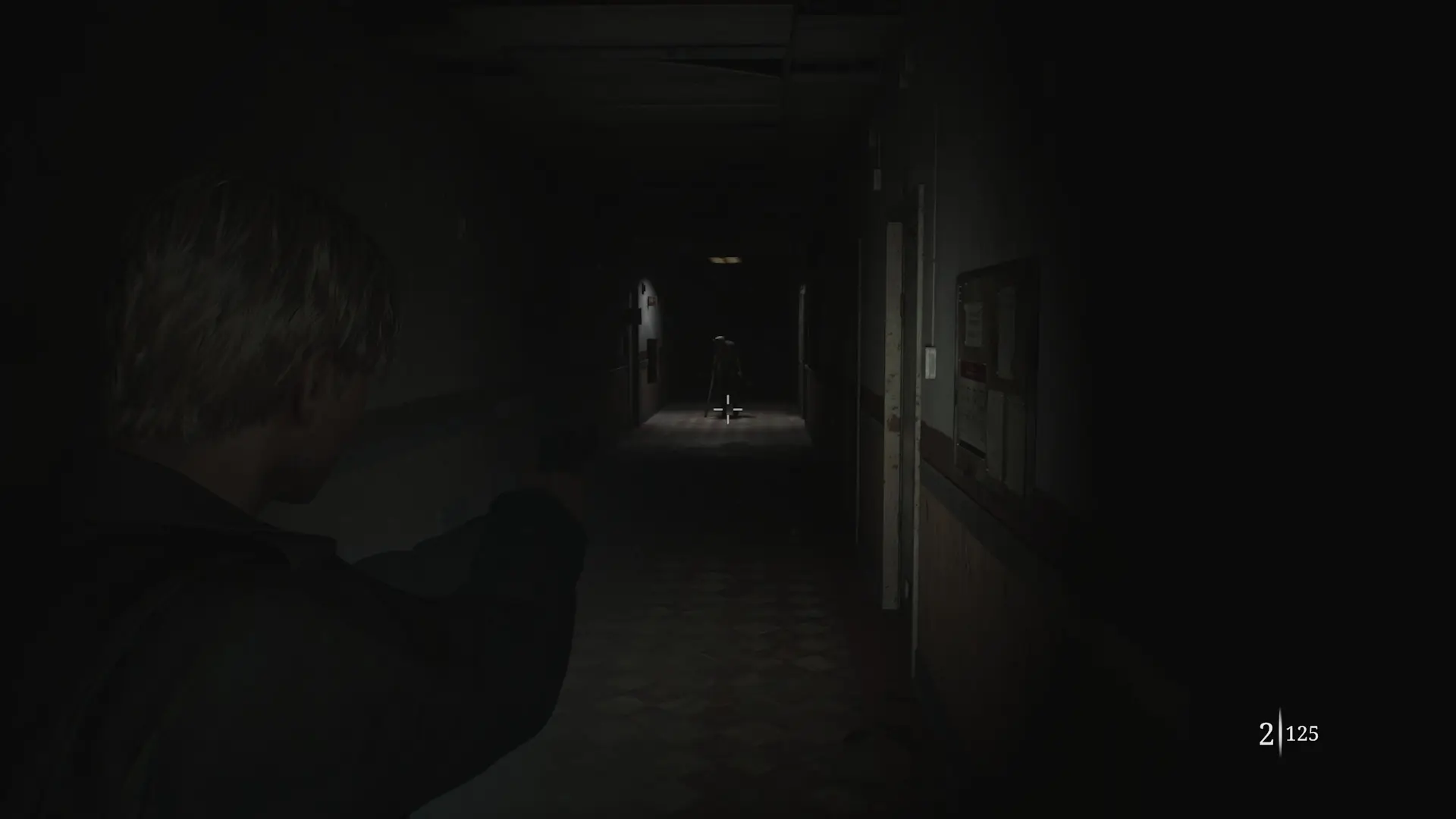 James aims his pistol at a nurse monster under a flickering light in the distance of a hospital hallway in silent hill 2