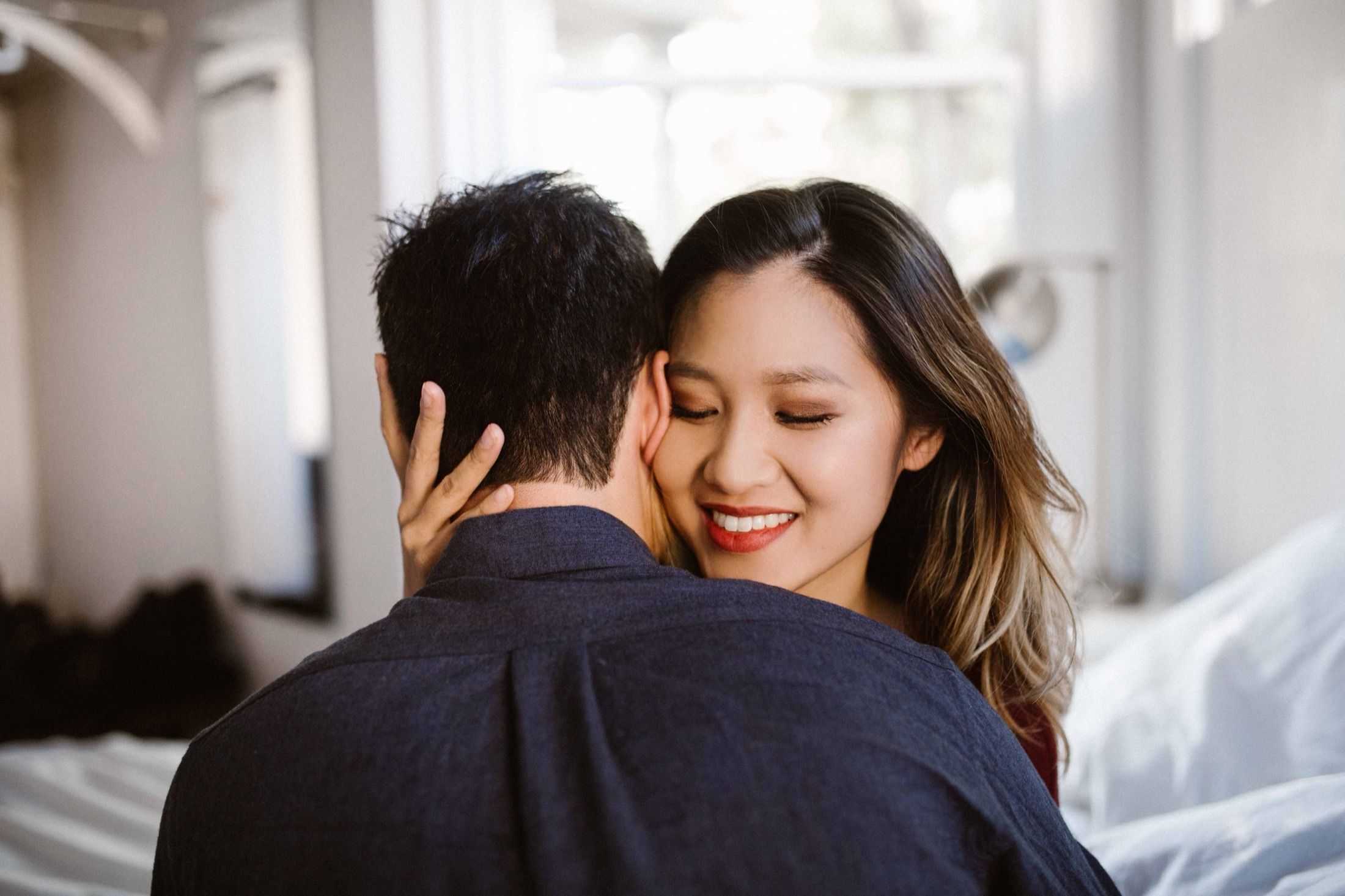 Annie and Logan embracing in their Seattle apartment, soft morning light.