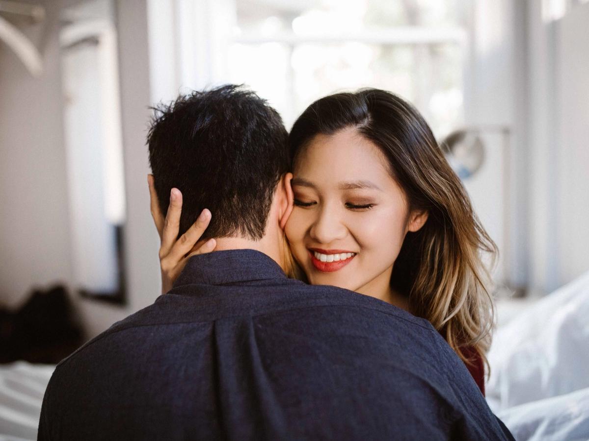 Annie and Logan embracing in their Seattle apartment, soft morning light.
