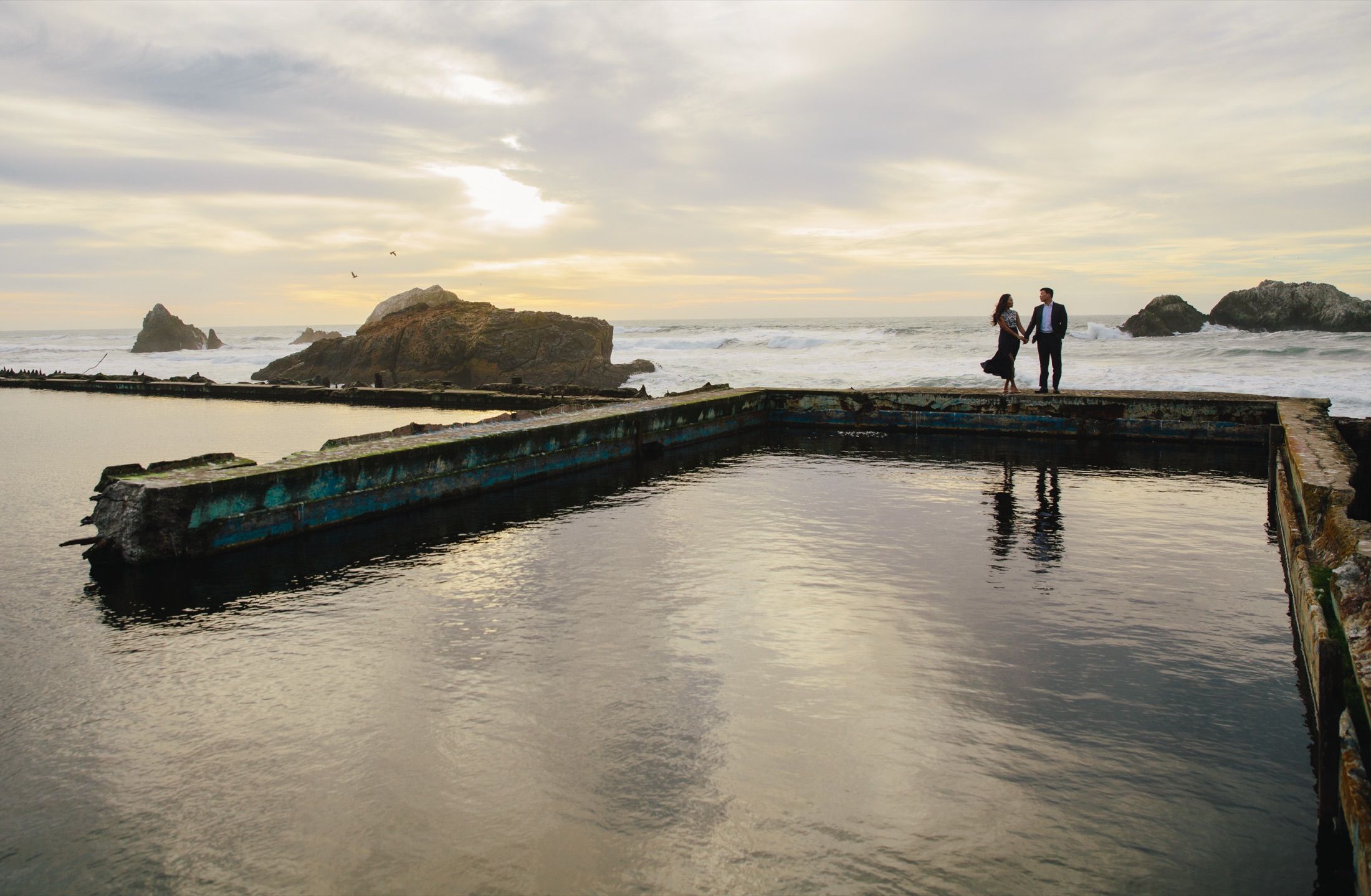 Tammy and Sang at the edge of the Sutro Baths ruins with the Pacific behind them.