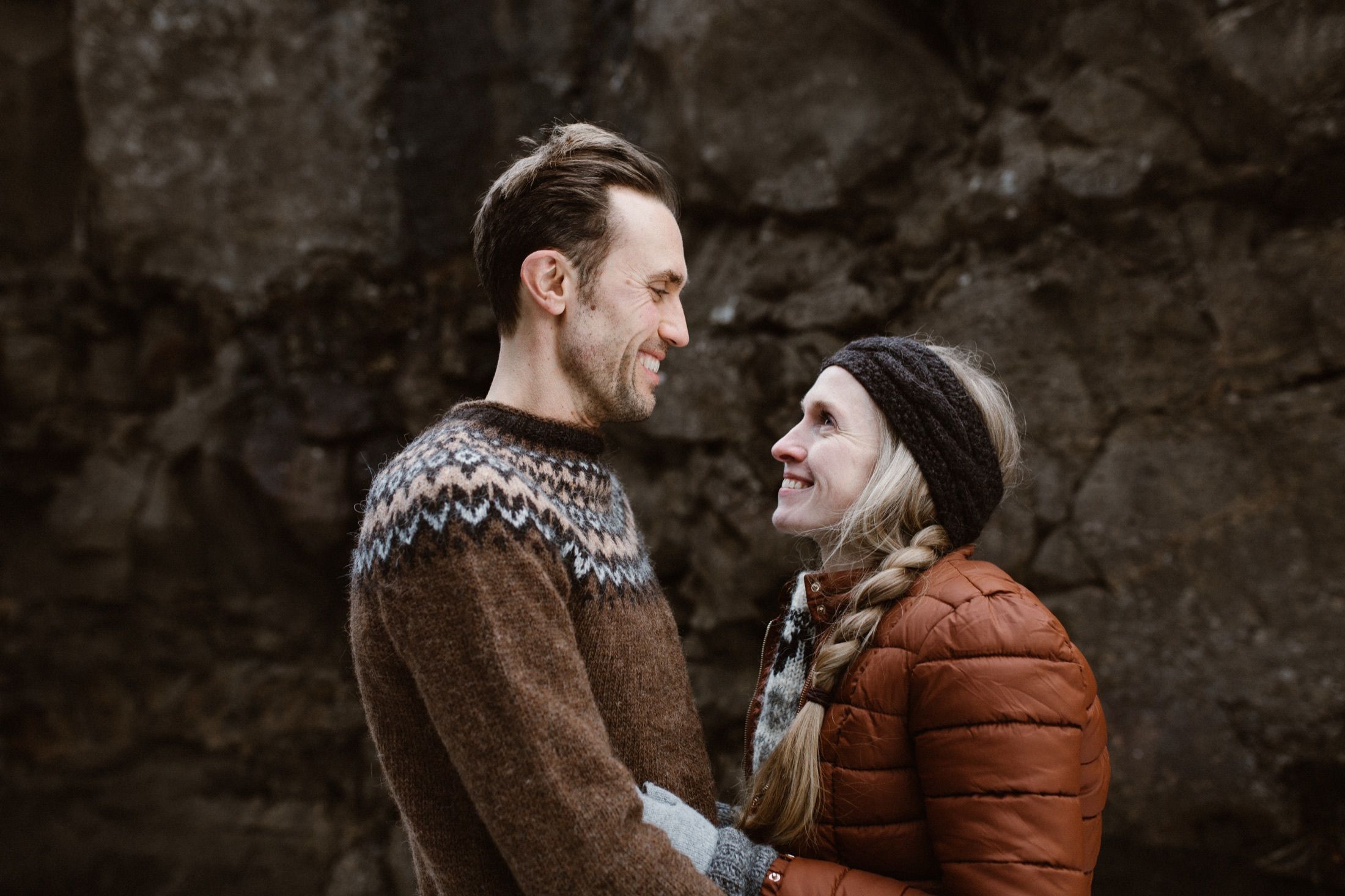 Halldora and Hobie embracing against red volcanic rock in Iceland.