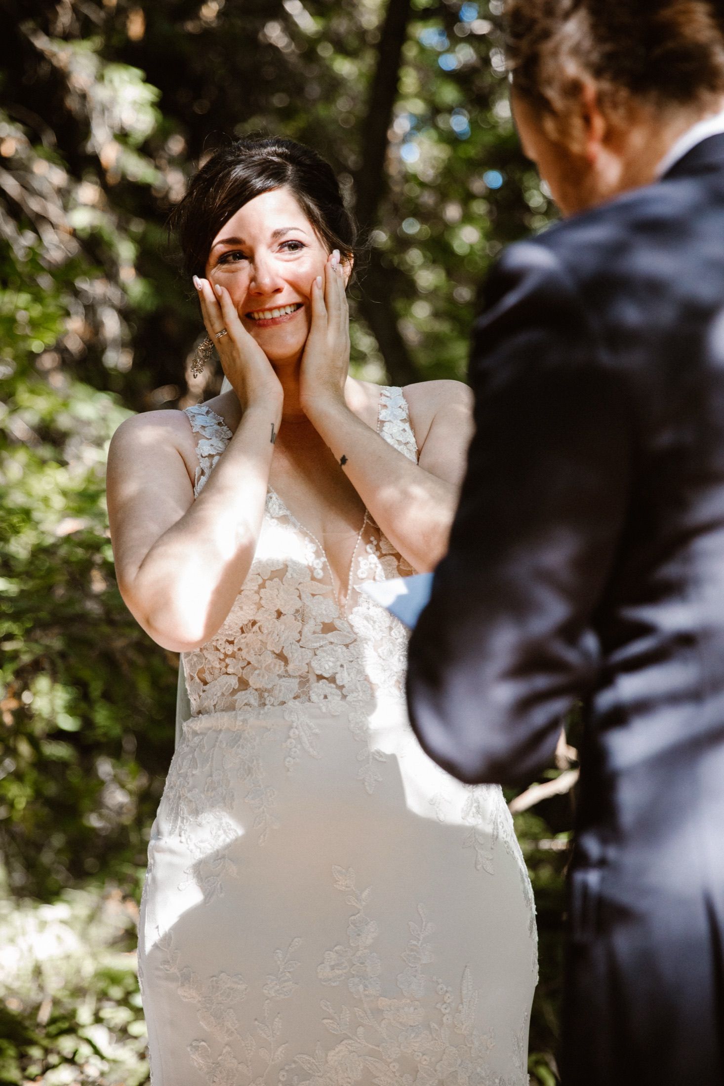 Josie holding her face during the first look, sunlit in the Big Sur redwoods.