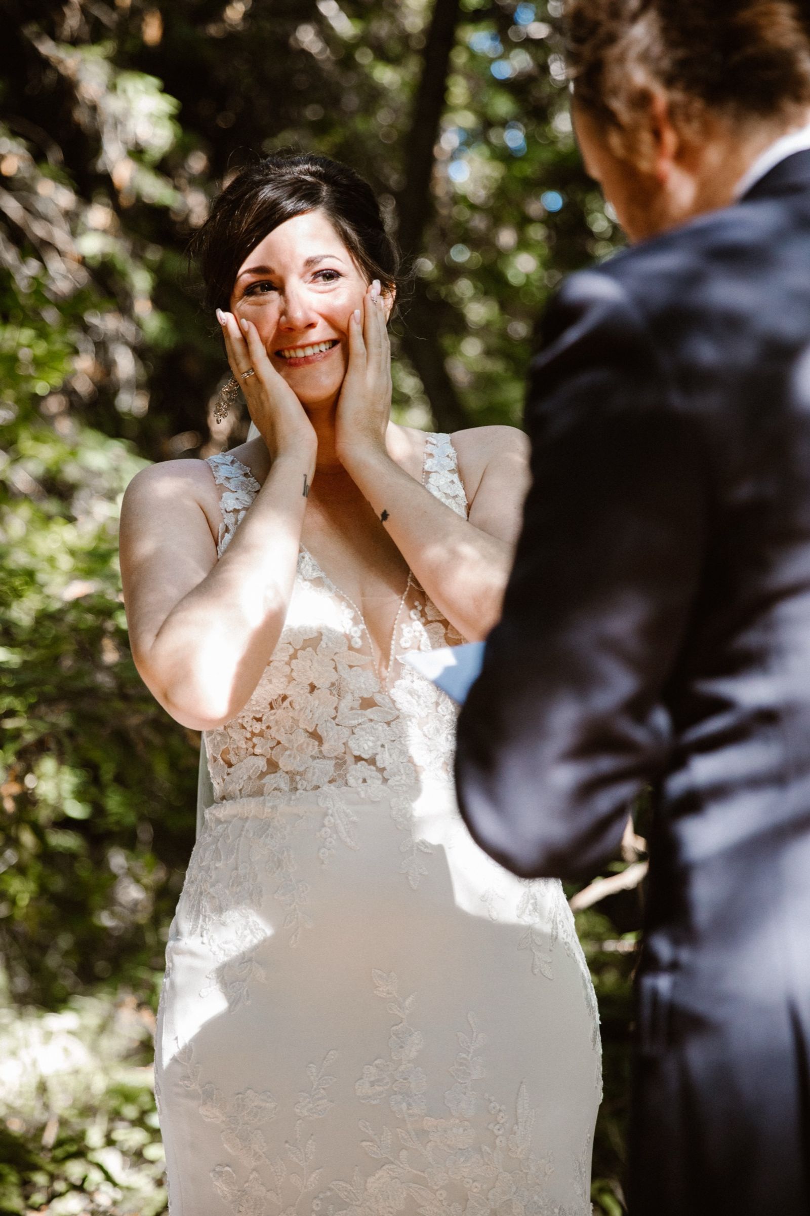 Josie holding her face during the first look, sunlit in the Big Sur redwoods.