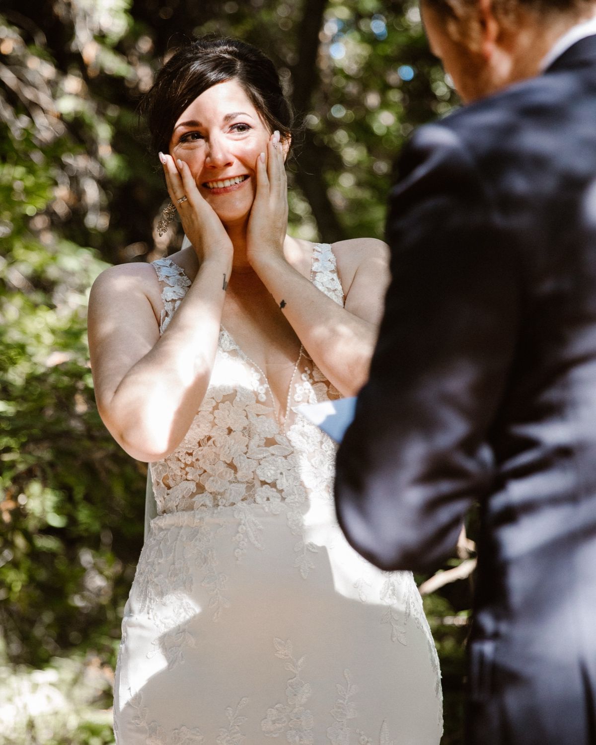 Josie holding her face during the first look, sunlit in the Big Sur redwoods.