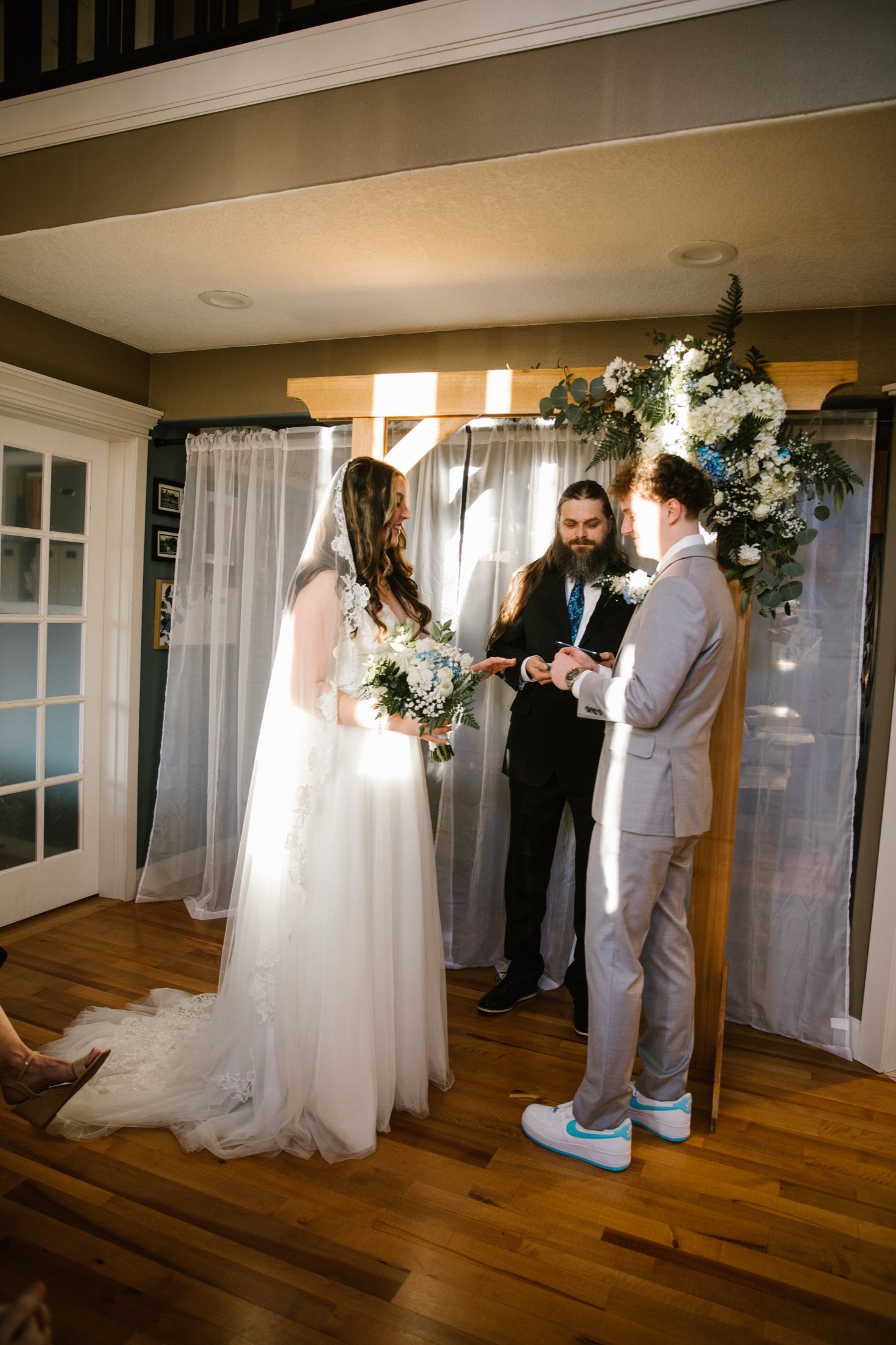 The Samuels at their indoor ceremony, beneath a floral arch and white curtains.