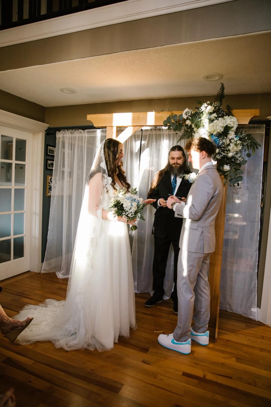 The Samuels at their indoor ceremony, beneath a floral arch and white curtains.
