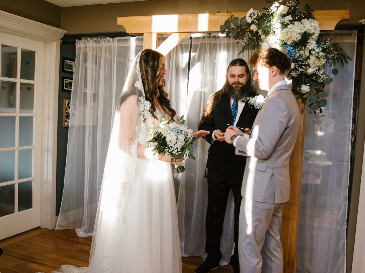 The Samuels at their indoor ceremony, beneath a floral arch and white curtains.
